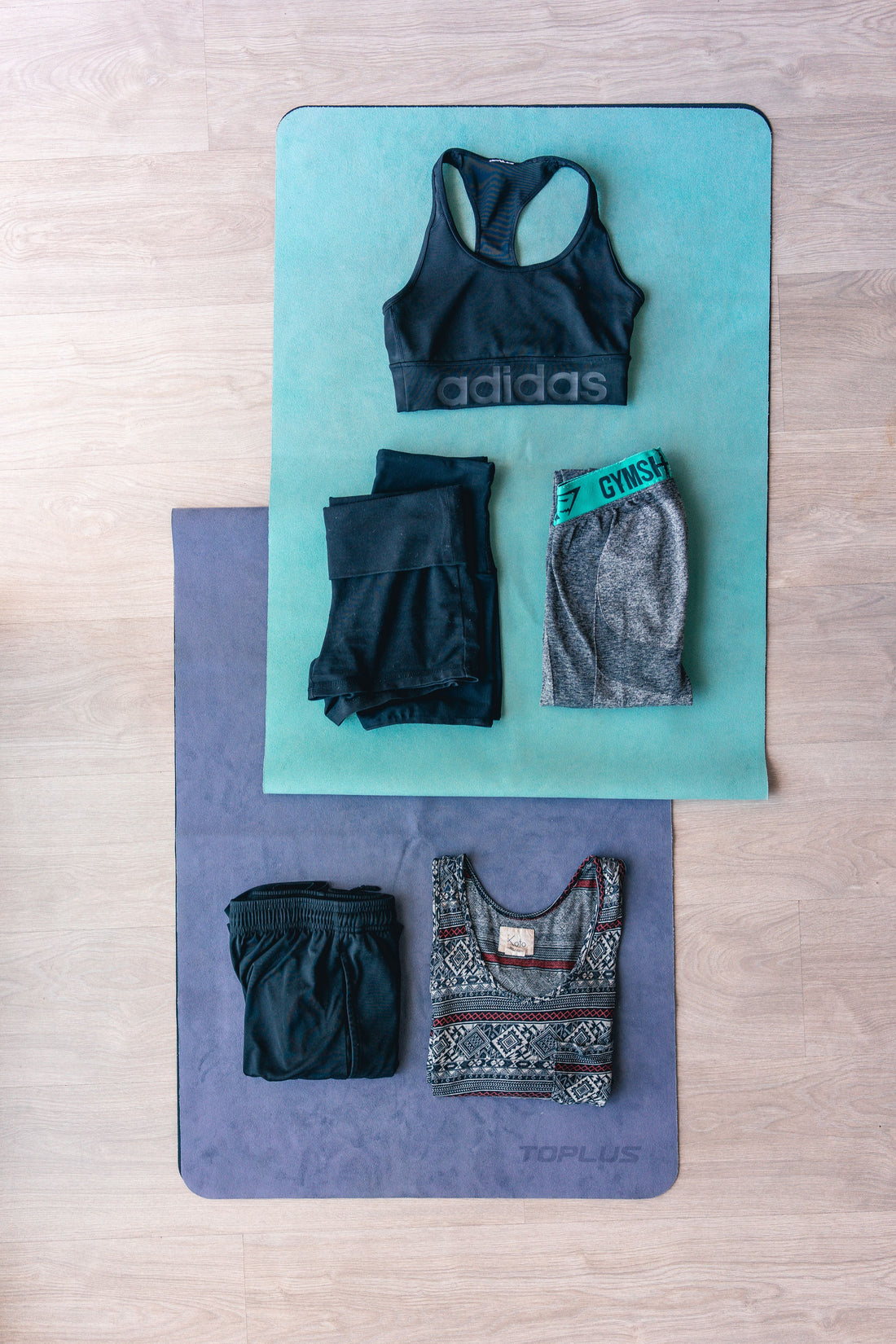 Flat lay of folded activewear including leggings and a sports bra, styled for a guide to shopping pre-owned activewear