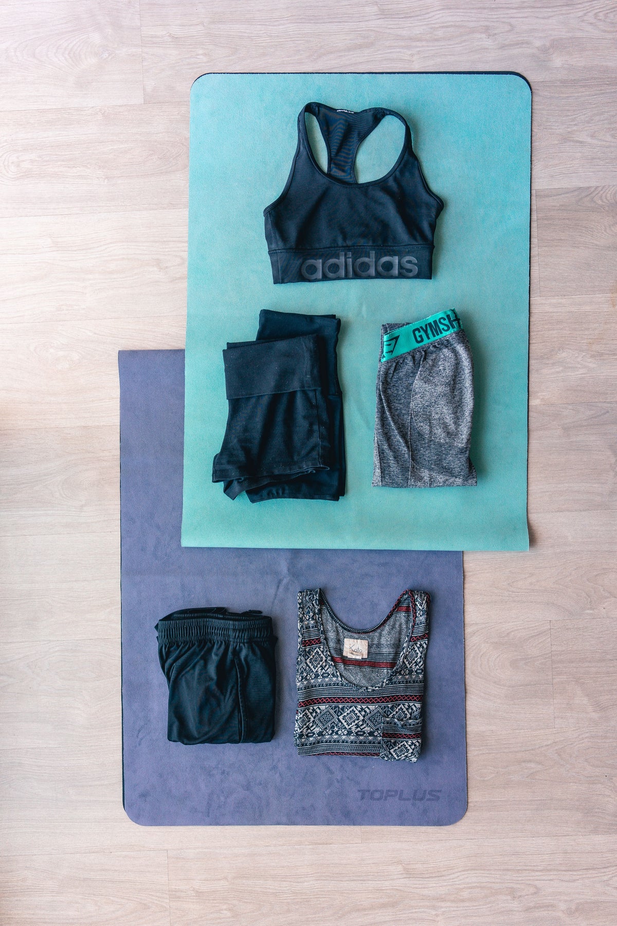 Flat lay of folded activewear including leggings and a sports bra, styled for a guide to shopping pre-owned activewear