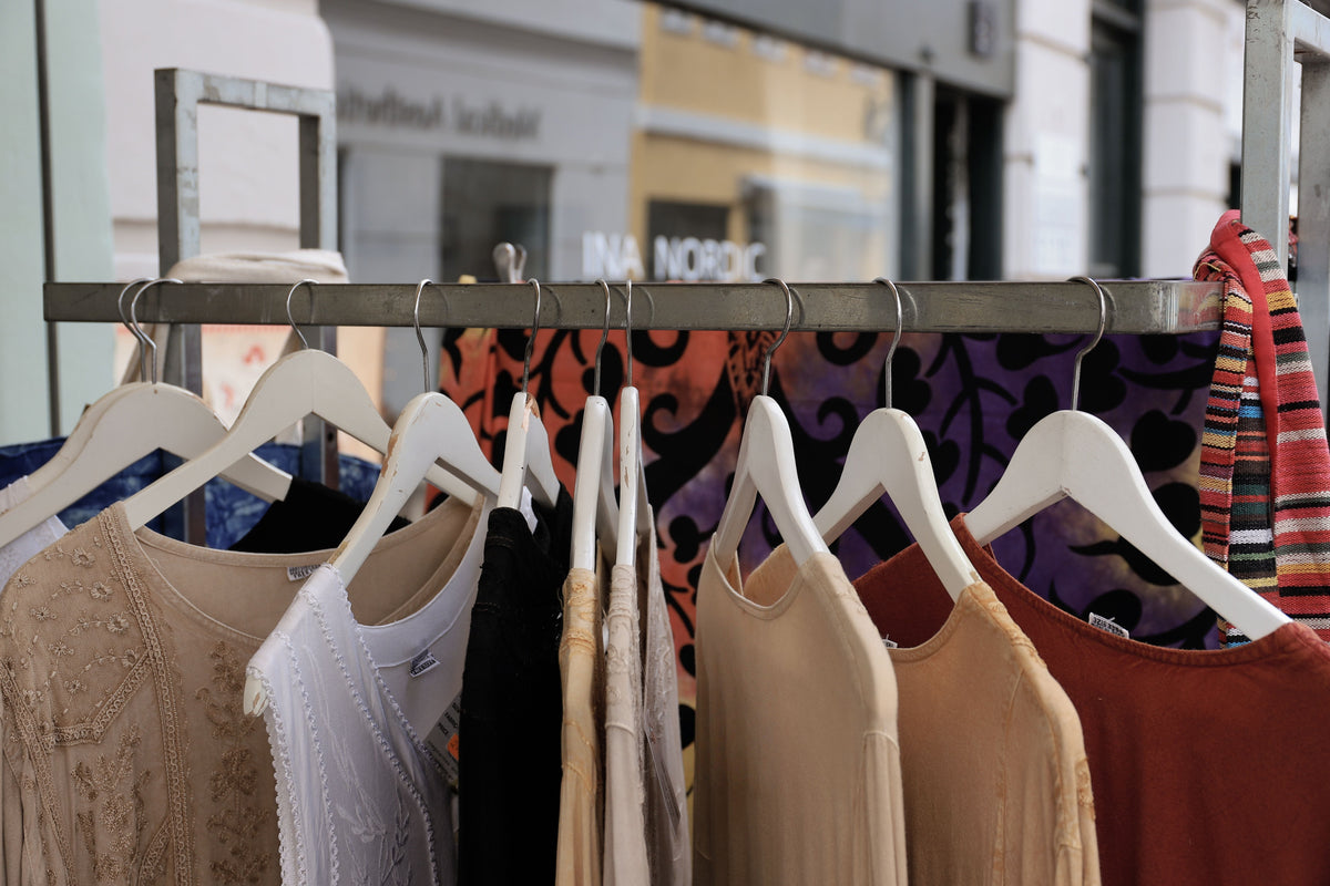 Colorful, textured clothing displayed on wooden hangers in a boutique, representing the eclectic mixed-print style collected in pre-owned Anthropologie pieces