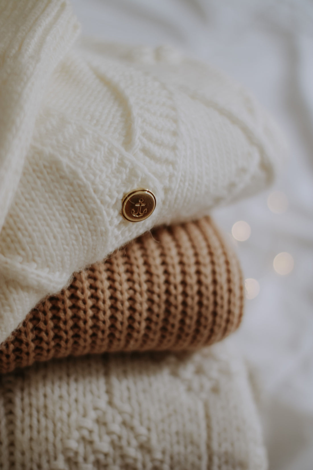 A stack of folded cashmere and knitted sweaters in warm neutral tones
