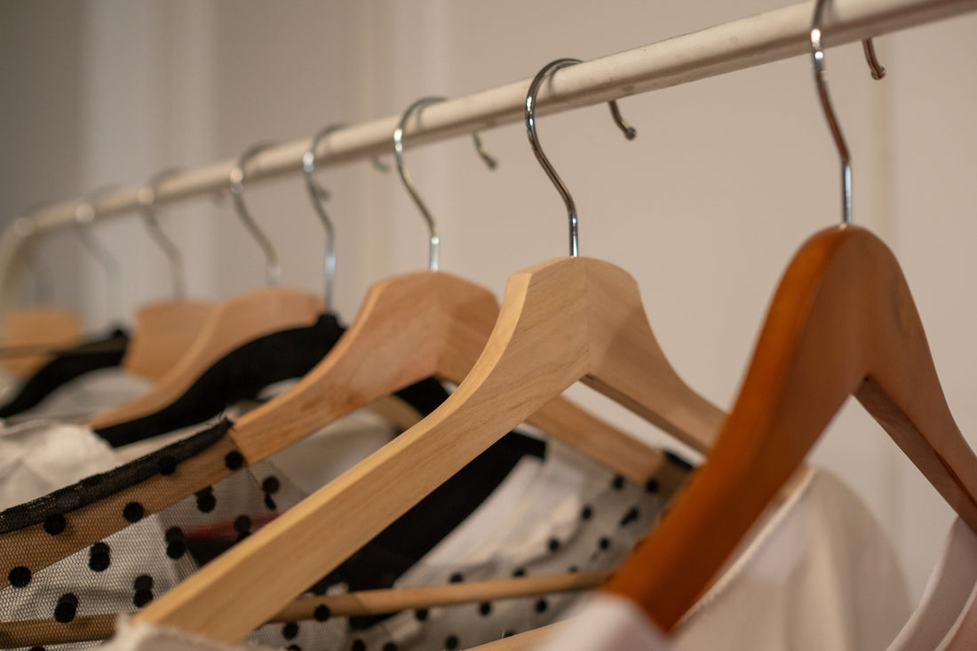 Close-up of wooden hangers with curated designer clothing in a boutique setting