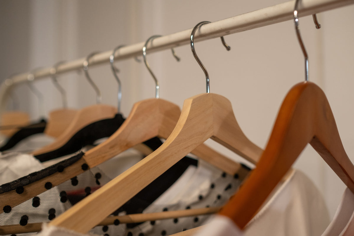Close-up of wooden hangers with curated designer clothing in a boutique setting