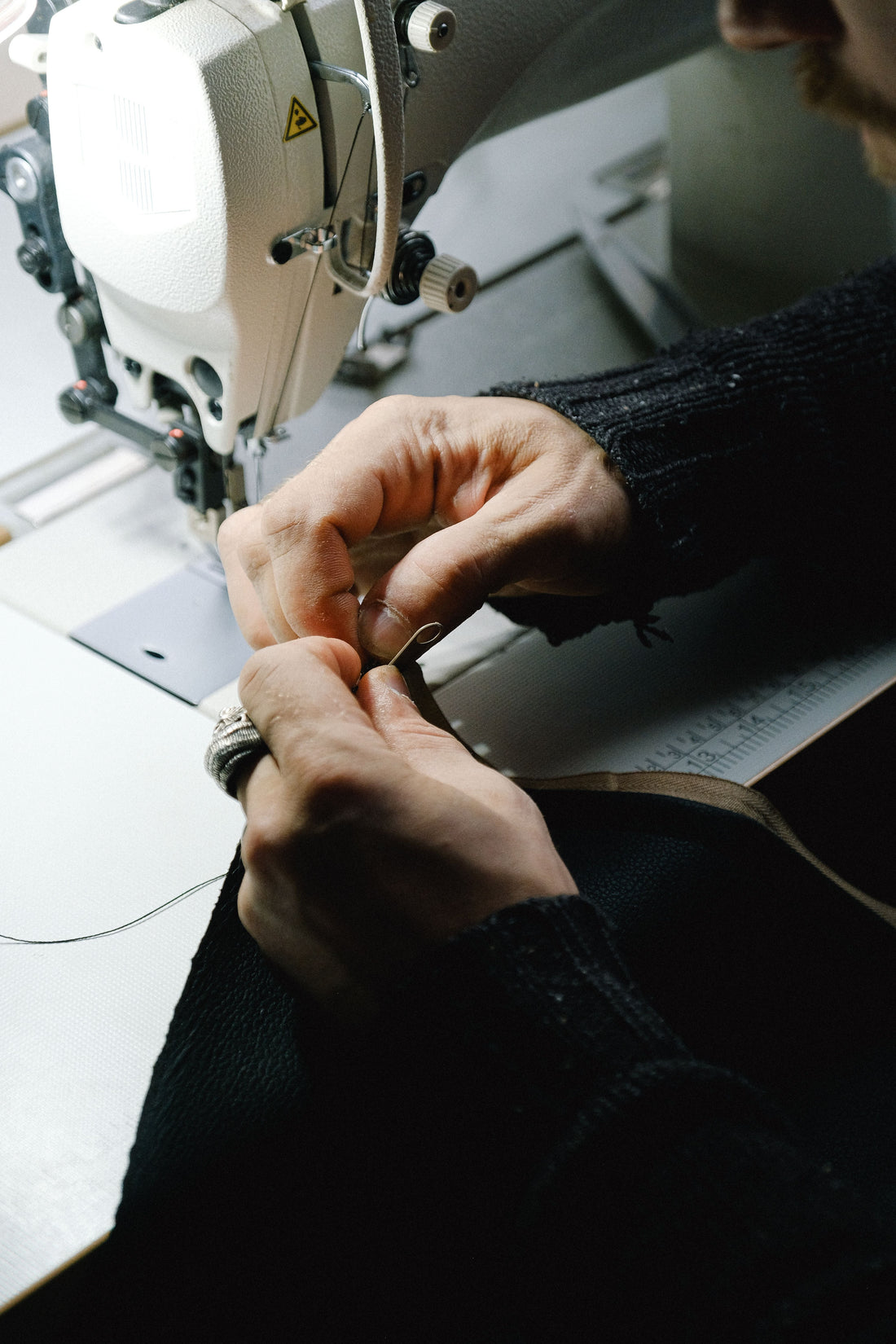 Close-up of hands closely examining fabric and stitching during a garment quality inspection