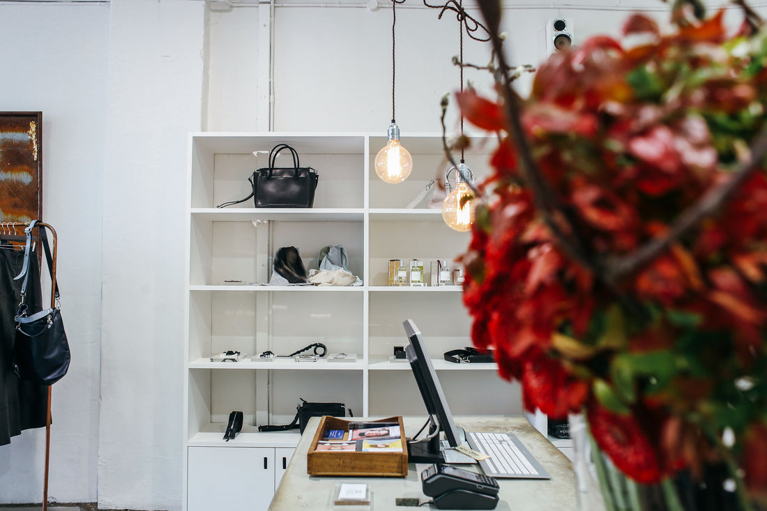 Designer handbags arranged on white wooden display shelves in a boutique
