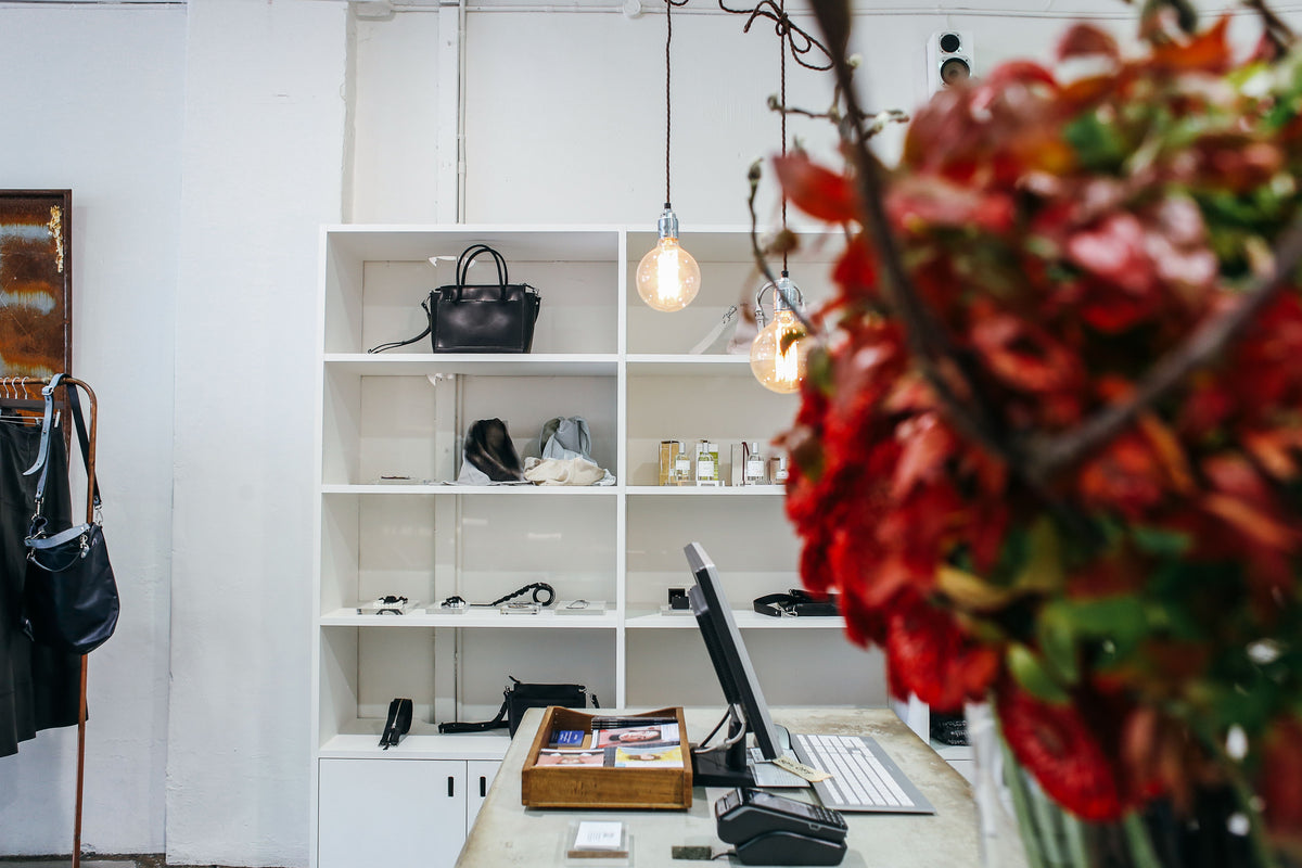 Designer handbags arranged on white wooden display shelves in a boutique
