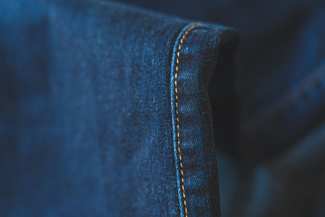 Macro detail of blue denim fabric showing stitching and seam construction
