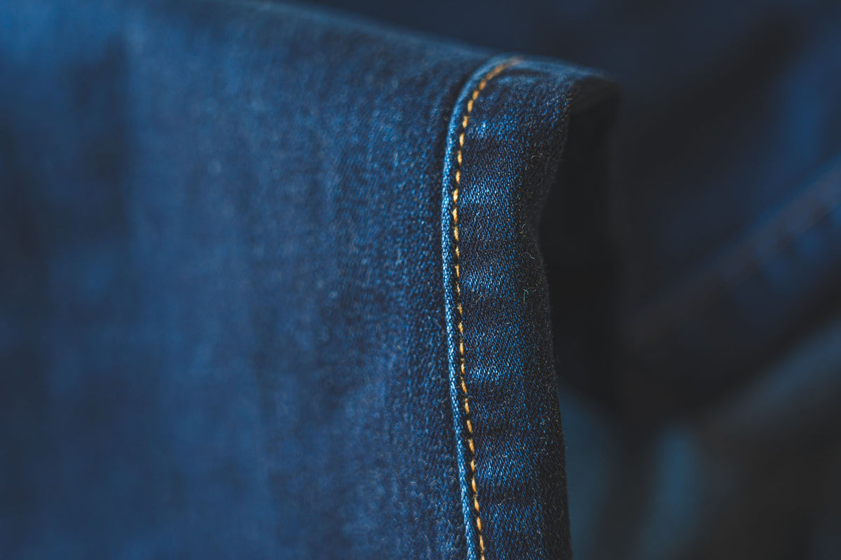 Macro detail of blue denim fabric showing stitching and seam construction