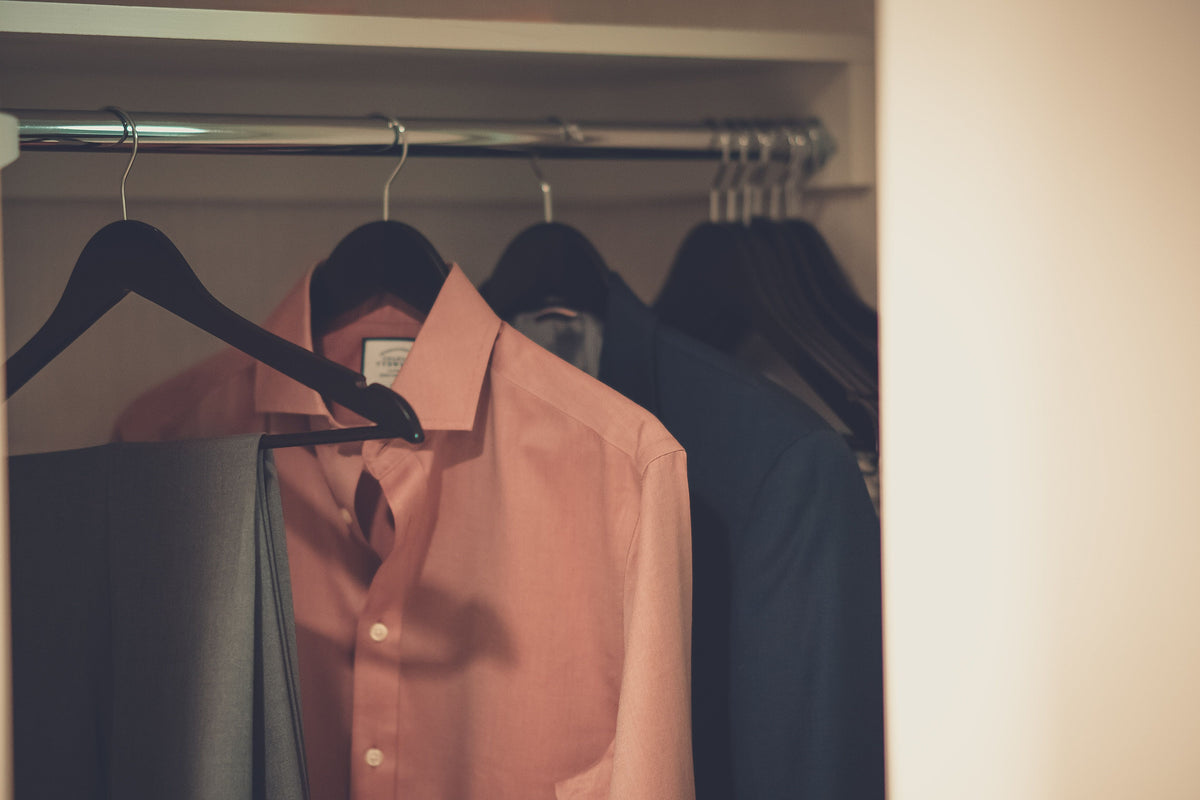 A stylish men's wardrobe featuring a tailored suit and dress shirt neatly hung on hangers