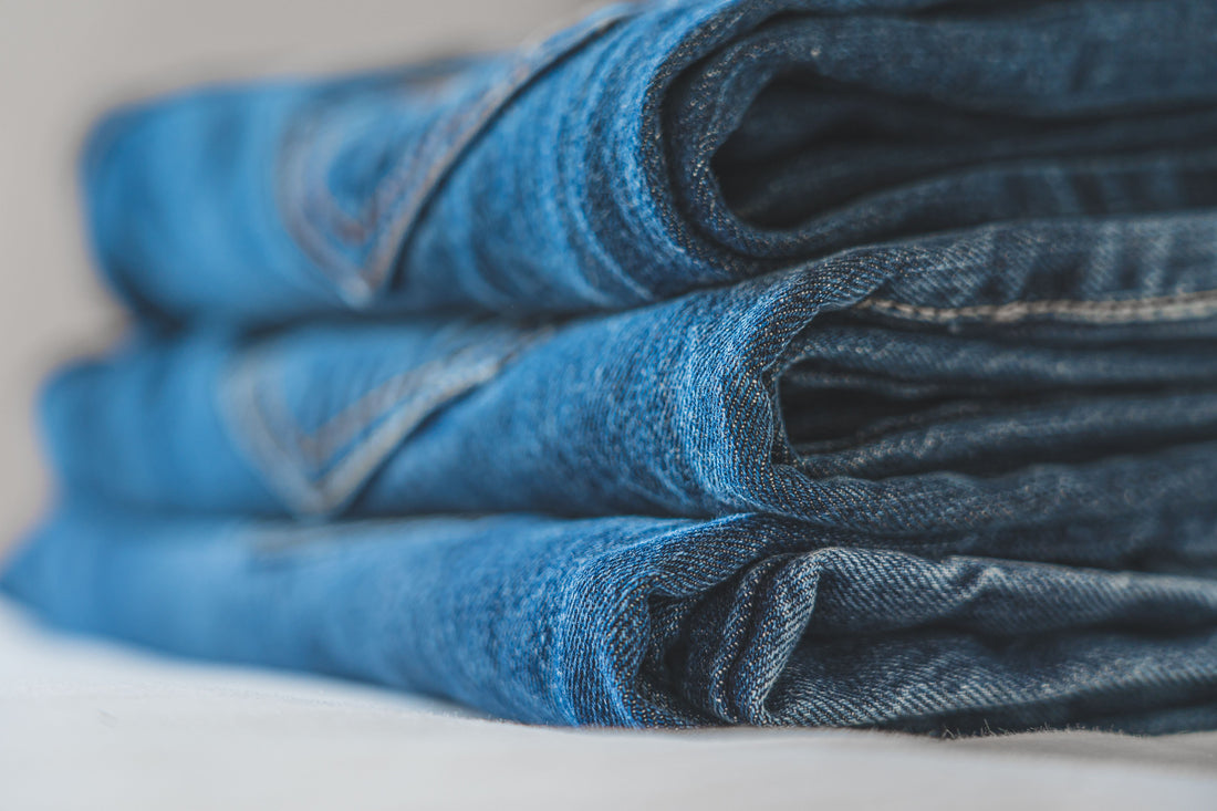 Neatly folded stack of blue denim jeans highlighting fabric texture and stitching
