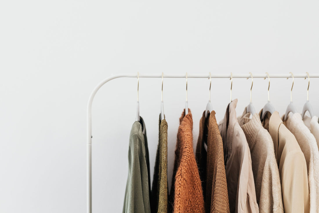 A minimalist clothing rack of neutral beige and brown-toned knitwear and jackets, representing the tonal wardrobe favored by quiet luxury designer brands