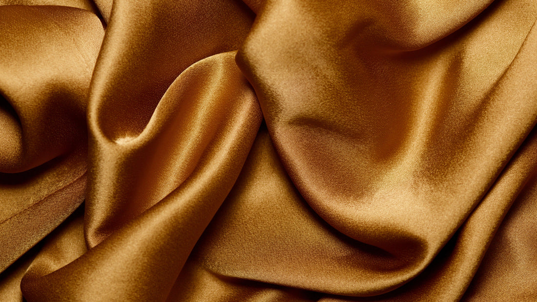 Close-up of smooth gold satin fabric with a soft, wavy sheen