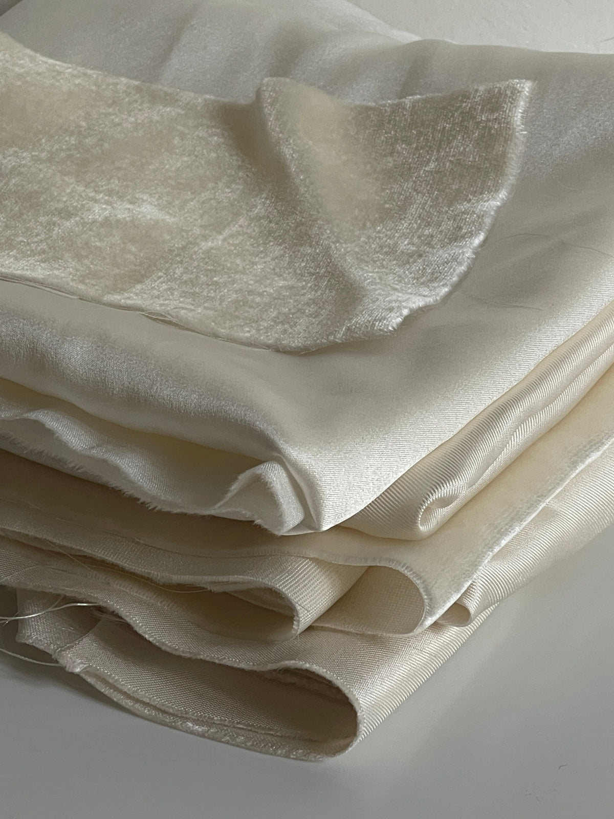 Ivory silk and velvet fabrics folded neatly in a stack