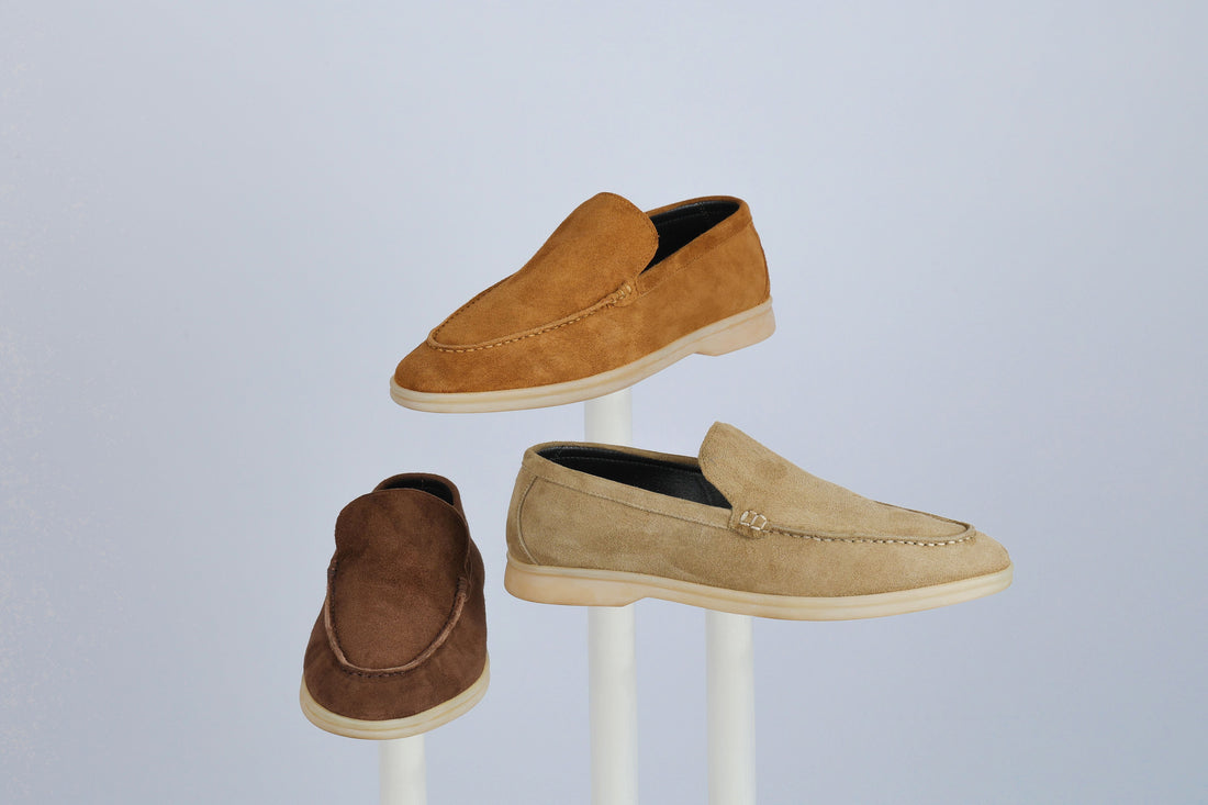 Trio of suede loafers in tan and brown tones displayed on minimalist stands