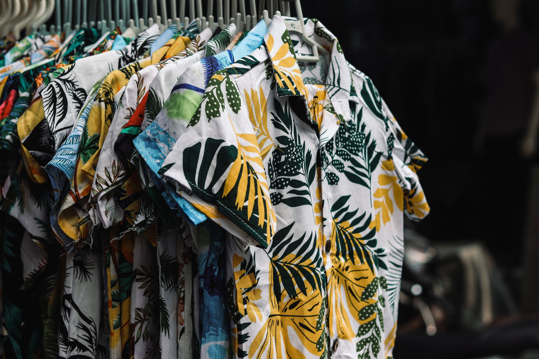 A rack of colorful tropical print camp shirts in a boutique, representing the resort-ready silhouettes collected in CENT'ANNII's guide to pre-owned Tommy Bahama
