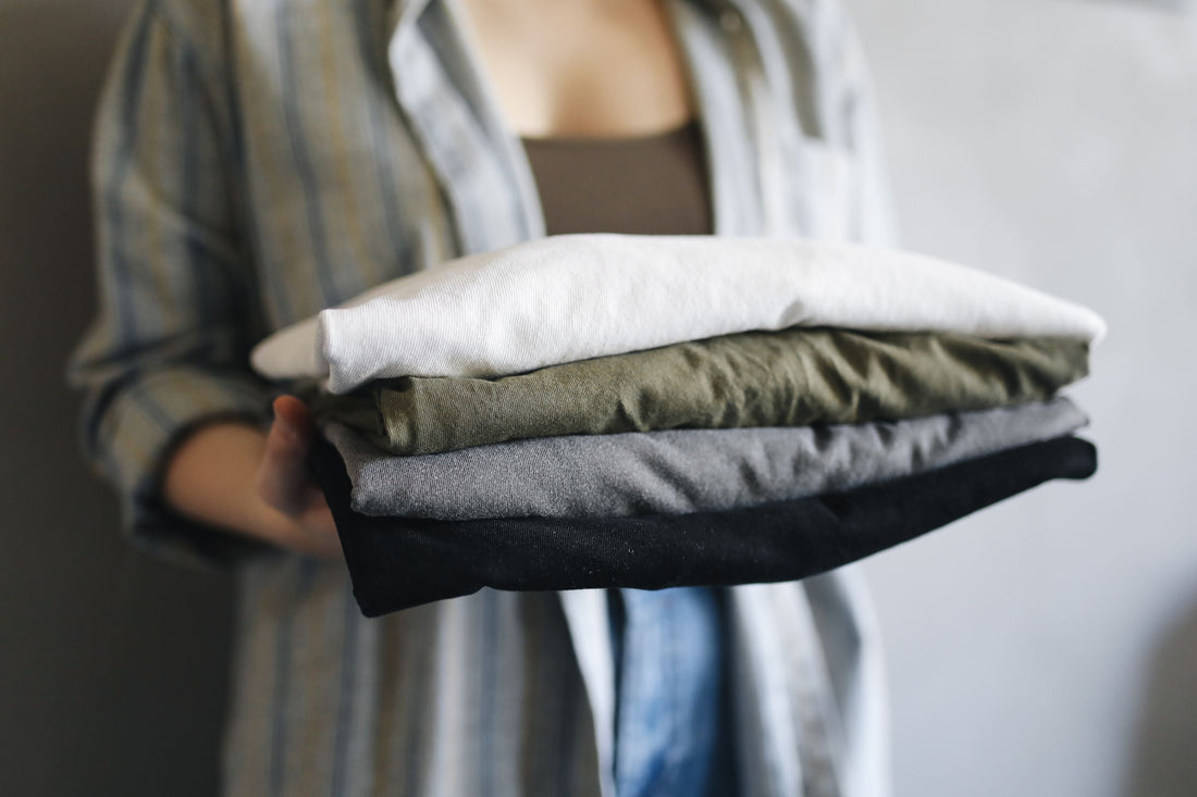 Neatly folded stack of cotton t-shirts and basics in earth tones
