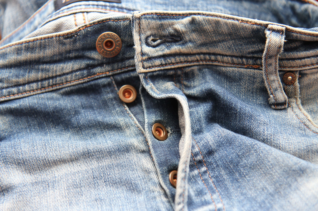 Detailed close-up of classic blue denim jeans with visible button fly, representing timeless vintage denim for CENT'ANNII's guide to Levi's eras and fits