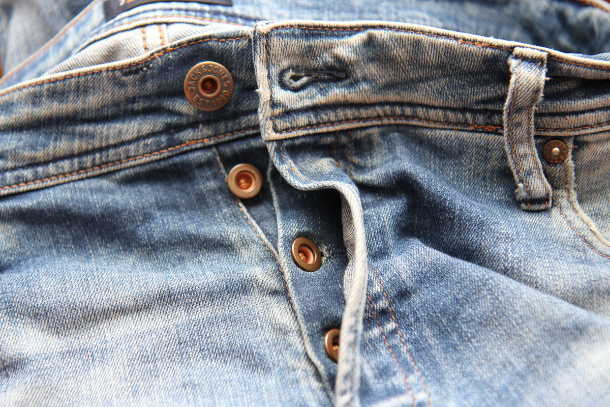 Detailed close-up of classic blue denim jeans with visible button fly, representing timeless vintage denim for CENT'ANNII's guide to Levi's eras and fits