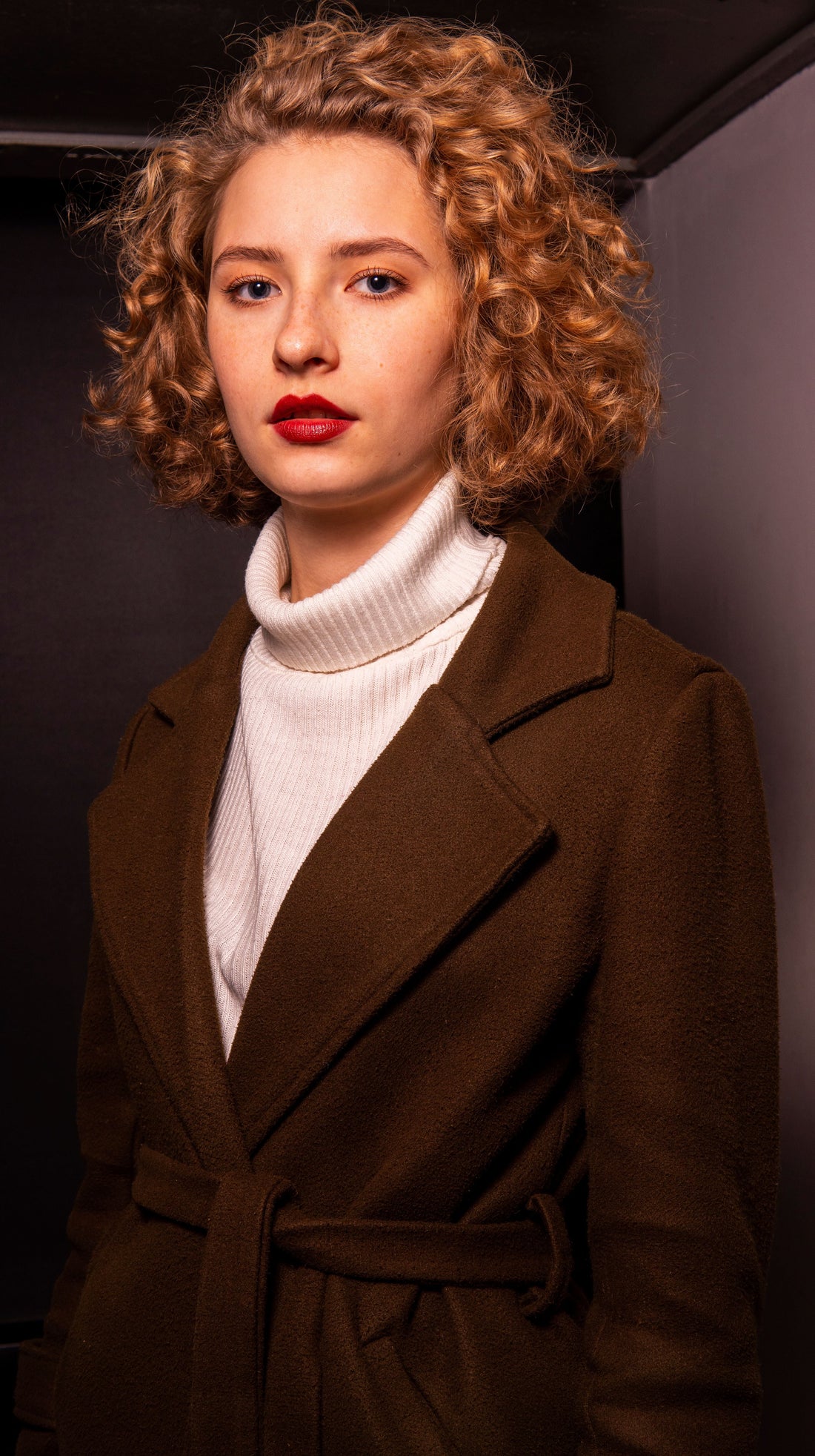 Woman in a brown wool coat and white turtleneck, an anchor look for a pre-owned winter capsule wardrobe