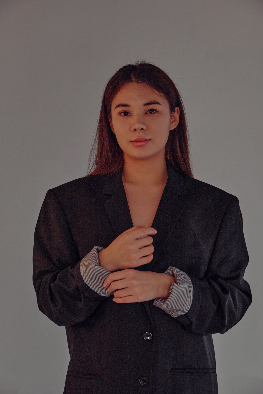 Portrait of a woman in a tailored black blazer against a neutral studio background, representing polished pre-owned workwear essentials