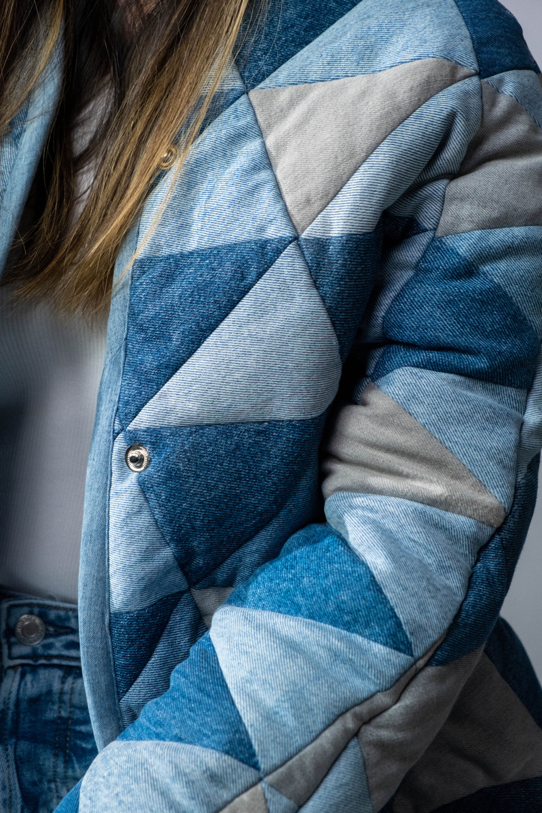 Close-up detail of a blue denim workwear jacket showing stitching and fabric texture