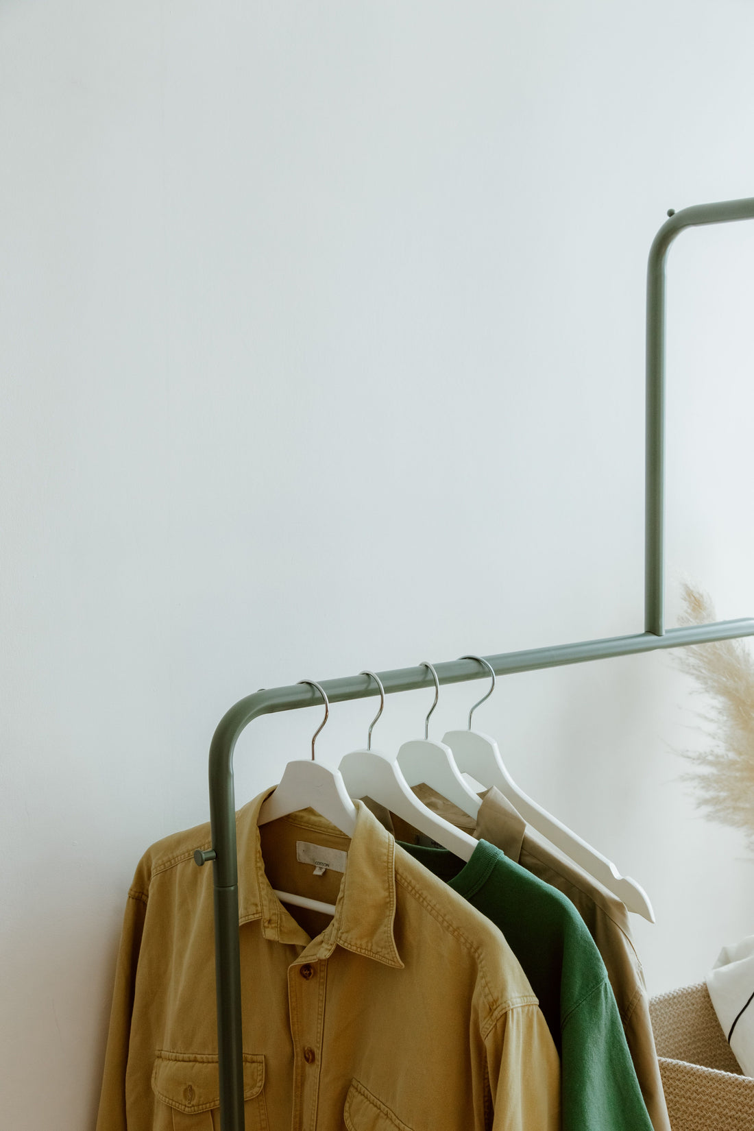 Neutral-toned graphic tees and shirts hanging neatly on a minimalist metal clothing rack
