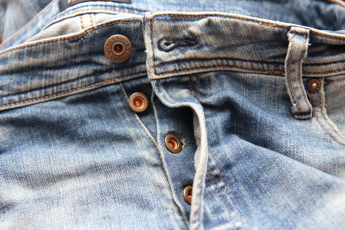 Detailed close-up of classic blue denim jeans with visible button fly, representing timeless vintage denim
